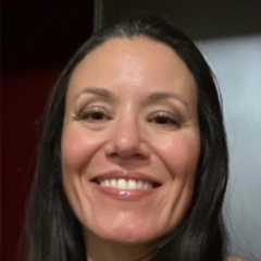 Smiling woman with long dark hair and makeup indoors