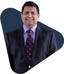 Pravin shukle, an educator, smiling in a suit.