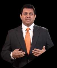 Pravin Shukle in a suit and tie presenting with hands gesturing