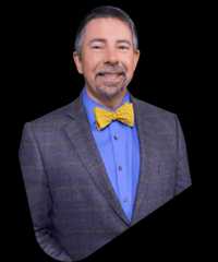 Sean Elliott smiling in a blue shirt, gray blazer, and yellow bow tie.
