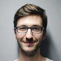 Alex r, a smiling young man with glasses and a beard.
