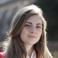 Laureen smiling outdoors with a blurred natural background.