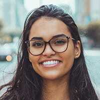 Young woman with glasses smiling outdoors, testimonial for lecturio.