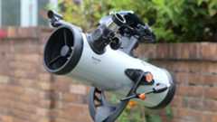 Celestron StarSense Explorer LT 114AZ pointing at the sky against a brick wall backdrop