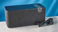 Klipsch The One Plus Bluetooth speaker in matte black photographed in front of a blue background.