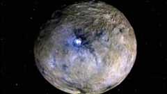 A gray rocky planet with blue lights on its surface glows in the darkness of space