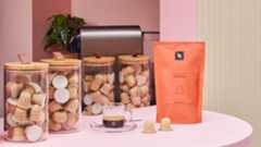 Nespresso paper capsules in jars on a countertop with a coffee bag