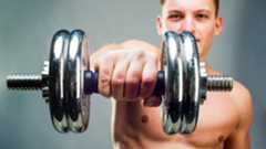 Man holding a dumbbell extended at shoulder height using an overhand grip close-up