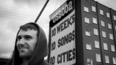 Fred Again with banner behind him that says USB002 10 weeks 10 songs 10 cities