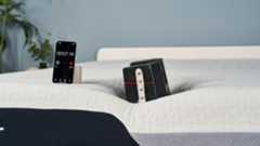 A 25kg is balanced on the edge of the Nectar Premier Memory Foam Mattress to test how far it sinks into the foam surface. A red laser line hits the weight's inch markers to pinpoint how deep the weight is sinking into the mattress's surface.