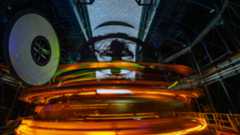 A long exposure image shows rings of glowing lights inside the dome of an observatory with streaks through the open dome showing the stars