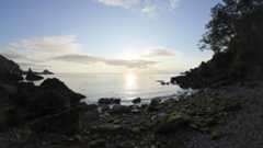 Early morning on a rocky beach with sunrise and calm seas