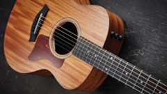 Close up of a Taylor GS Mini acoustic guitar lying on a wooden floor