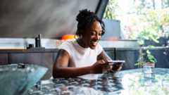 A young black woman playing a mobile game on the Samsung Galaxy S25 in a stylish kitchen