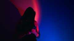 photo of a woman looking at a phone under stark red and blue light