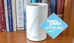 A TP-Link Deco BE63 Wi-Fi 7 mesh router on a bookshelf with a Tom's Guide Prime Day deals badge