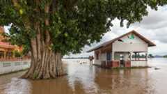 Flood waters rise to the porch of a house next to a tree in Laos