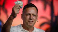 Peter Thiel holds hundred dollar bills during a Bitcoin conference in Miami