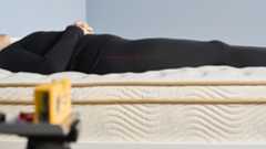 One of our mattress testers lies on her back on the Saatva Classic, with her hands folded comfortably on her stomach. A digital laser measure traces a straight line down the side of her body so we can see the excellent spinal alingment the Saatva Classic mattress delivers during back sleeping. Our tester is comfortable, with the mattress contouring her body lightly while keeping it firmly on top to prevent any sagging of her spine. That's crucial for preventing back pain