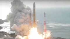 an orange and white rocket lifts off from its seaside launch pad