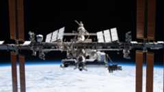 a T-shaped space station floats above Earth