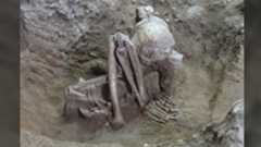 a tightly crouched human skeleton in the ground