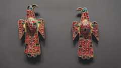 A pair of eagle-shaped bronze brooches inset with red, blue, and white stones