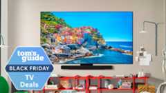 The LG C5 in a wall-mounted position displaying a pastel-colored Italian coastline. Overlaid is a badge that reads: "Tom's Guide Black Friday TV Deals"