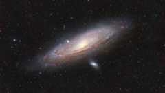 A large spiral galaxy is pictured shining against a colorful starfield.