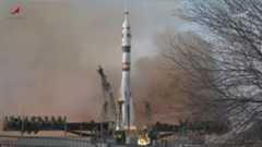 A white rocket is pictured lifting-off from a launch site in Russia. Fiery exhaust and smoke is visible pouring from the rocket&#039;s engines as it lifts into a grey sky.