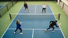 A group of four young adults play pickleball.
