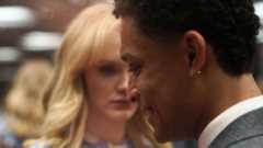 A man laughs while half a woman's face can be seen in the background