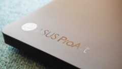 A black ASUS ProArt P16 laptop on a green sofa