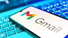 A smartphone with the Gmail logo on it resting on top of a computer keyboard.