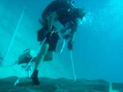 A NEEMO engineering crew diver simulates anchoring to an asteroid surface.