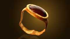 Gold ring with gemstone against spotlight on black background.