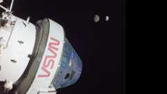 A large white space shuttle labeled in red "NASA" is seen in the darkness of space.