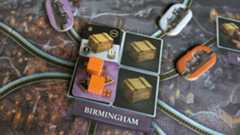 Orange cubes, crate tokens, and train tokens surrounding the Birmingham place setting on the Brass: Birmingham board