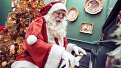 Santa Claus playing piano in front of a Christmas tree