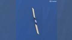 closeup photo taken from space of a boxy satellite with long, rectangular solar arrays extending on either side of its body