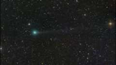 a green comet with a faint tail in the sky against a backdrop of stars