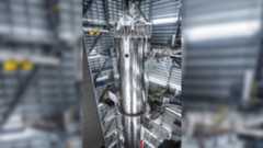 a tall silver rocket upright in a hangar