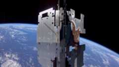 a metal cube-shaped device in the foreground with a blue-and-white earth in the background