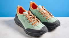 the keen jasper zionic hiking shoes in green/gold colorway photographed against a blue tom&#039;s guide background and a stone floor, showing the lug sole and the leather upper with orange laces