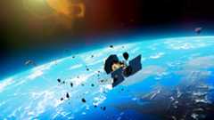 an illustration of a cylindrical satellite breaking apart into multiple pieces above earth