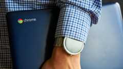 Man holding Chromebook at is side with smart watch visible on wrist
