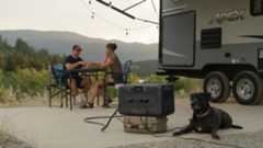 Couple camping in a UV with their dog, using a portable power station