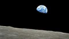 A photo of the Earth in the darkness of space with the surface of the moon in the foreground of the image
