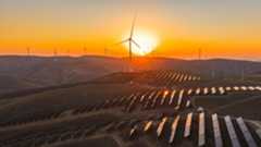 solar panels and wind turbines on rolling hills at sunset