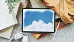 Drawing apps for iPad; a cloud and sky painted on a ipad, which sits on a coat on a table